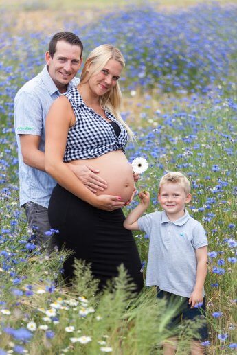 Junge Familie im Blumenfeld während der Schwangerschaft der Mama