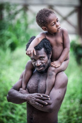 Ureinwohner Papua mit kleiner Tochter auf den Schultern