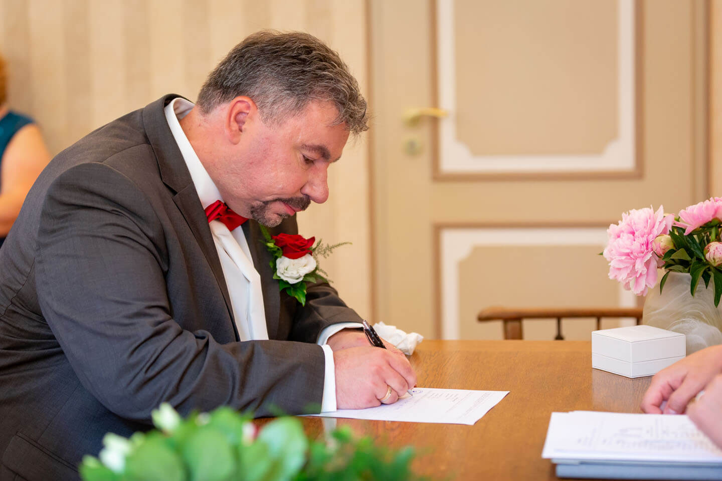 Bräutigam unterschreibt im Standesamt die Heiratsurkunde