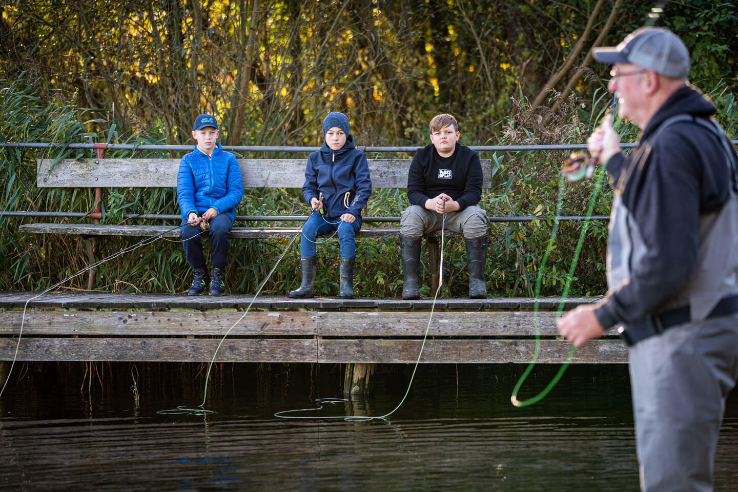Unternehmensfotografie Outdoor: Lehrer Knuthsen erklärt seinen Schülern das Werfen mit der Fliegenrute