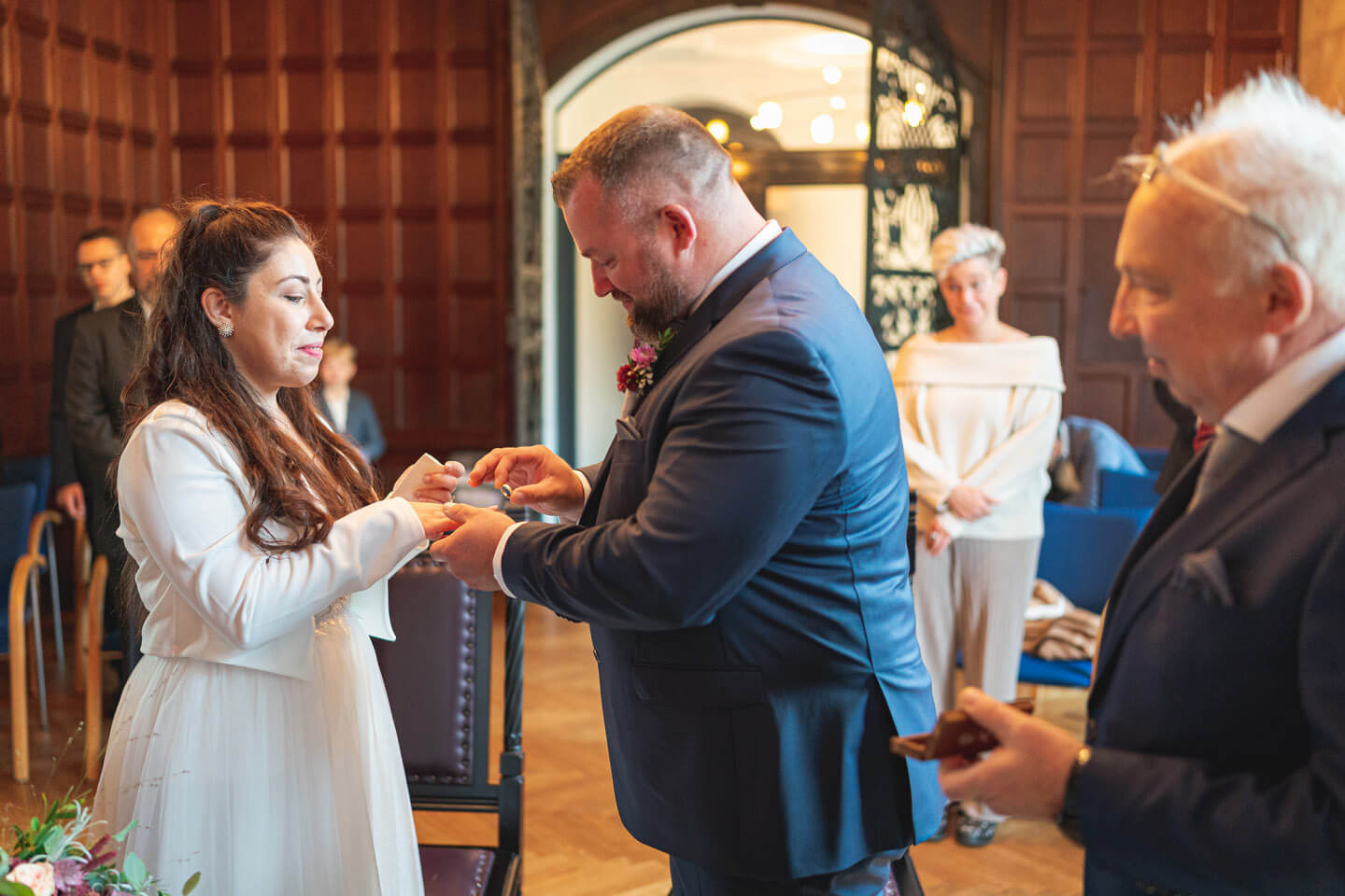 Bräutigam steckt der Braut den Ring auf.