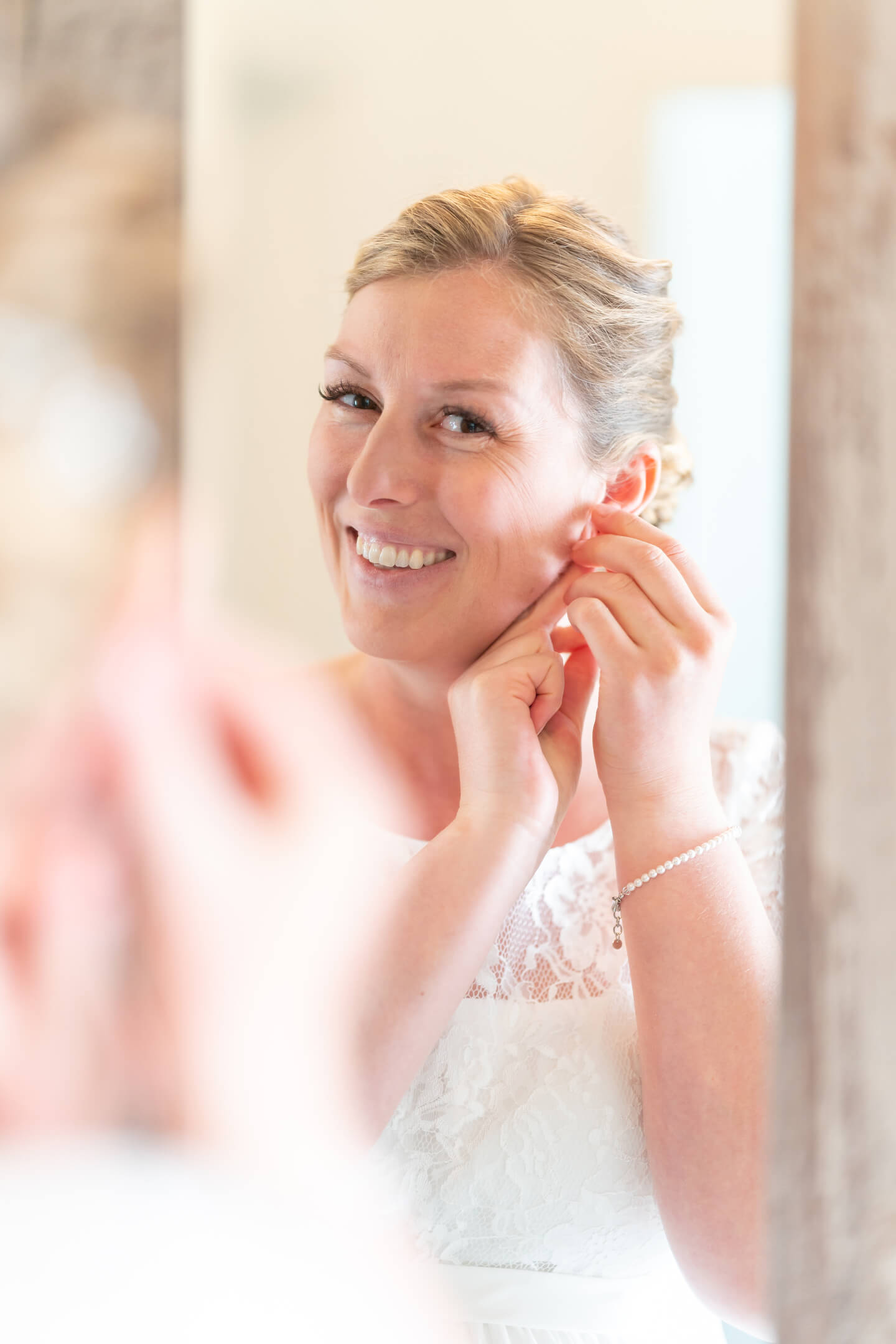 Getting Ready fotografieren: Braut steckt sich die Ohrringe ins Ohr.