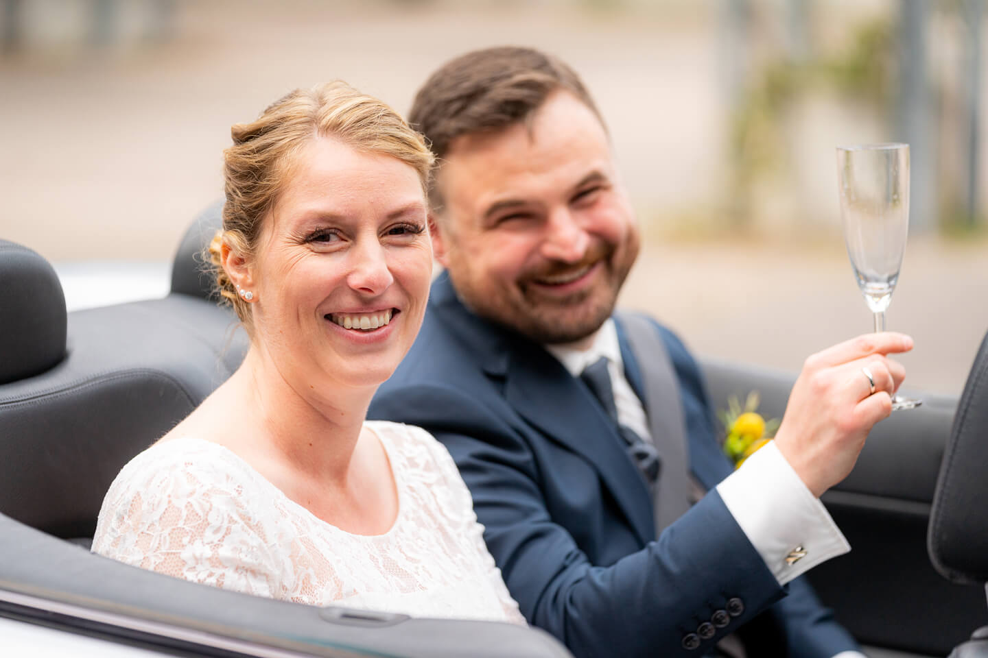 Cheers! Brautpaar im Hochzeitsauto.