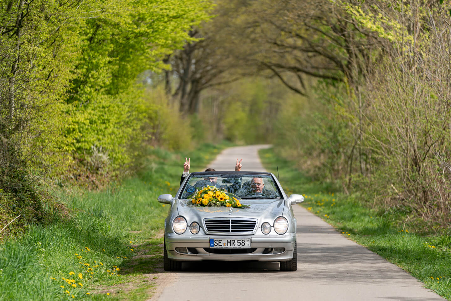 Hochzeitsauto mit gelbem Blumenschmuck.