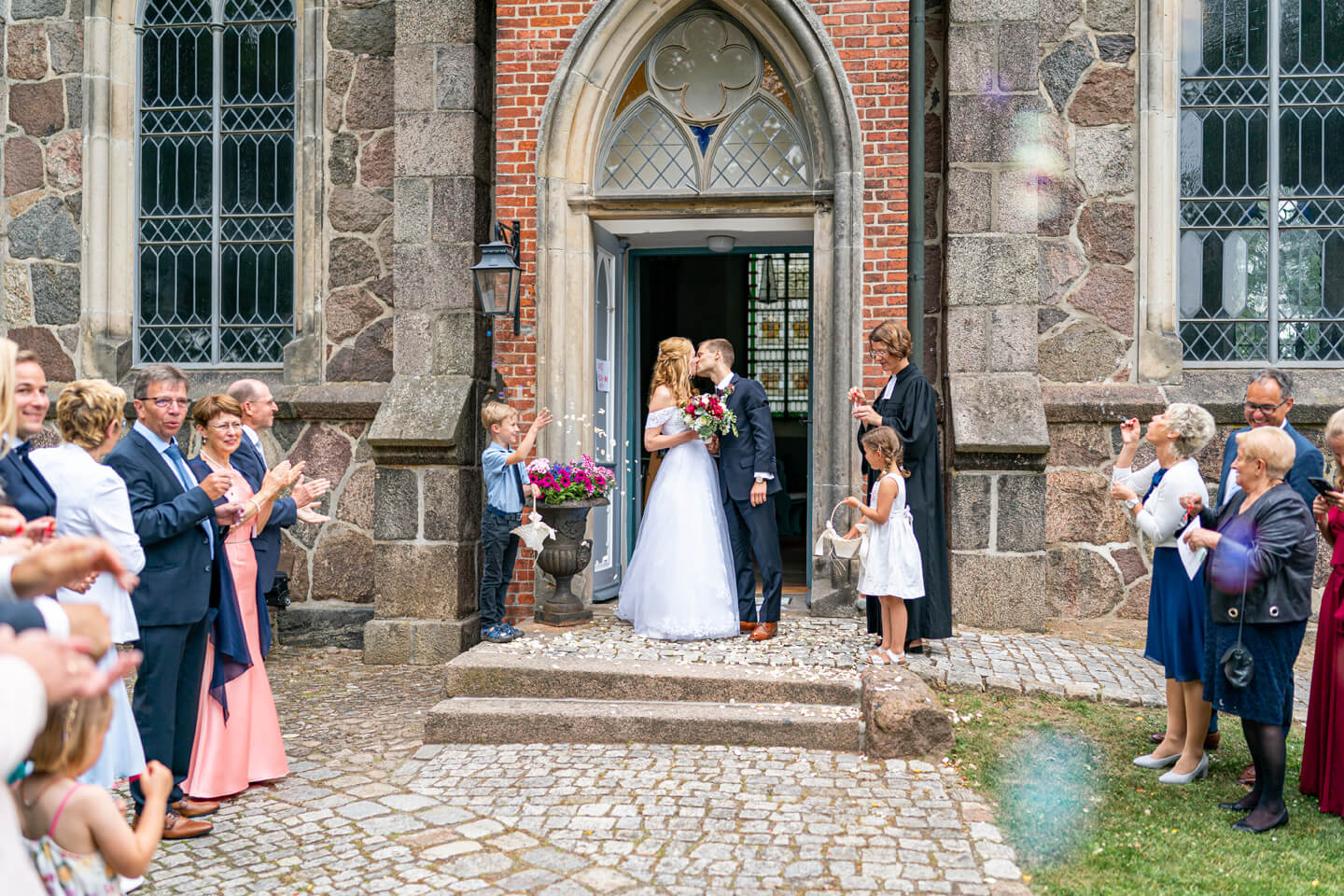 Frisch verheiratet in der Kirchentür. Das Brautpaar küsst sich.