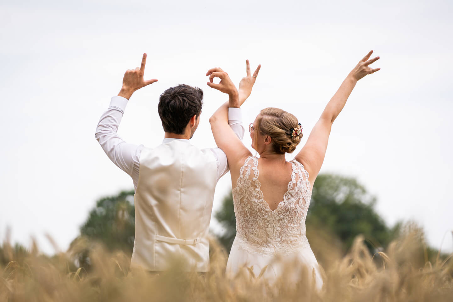 Hochzeitspaar zeigt das Wort LOVE mit ihren Fingern.