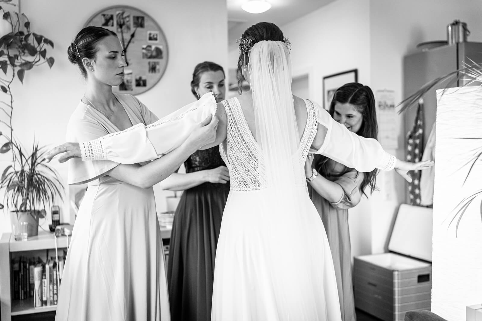 Freundinnen helfen der Braut beim Kleid anziehen während des Getting Ready.