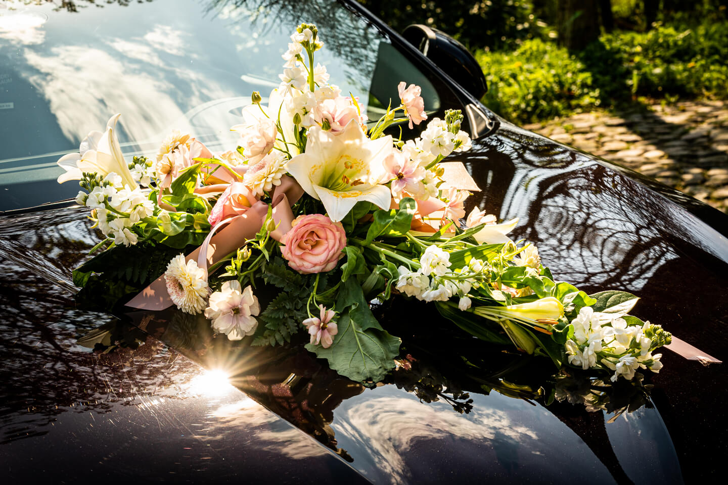 Blumenschmuck auf dem Hochzeitsauto im warmen Sonnenlicht.