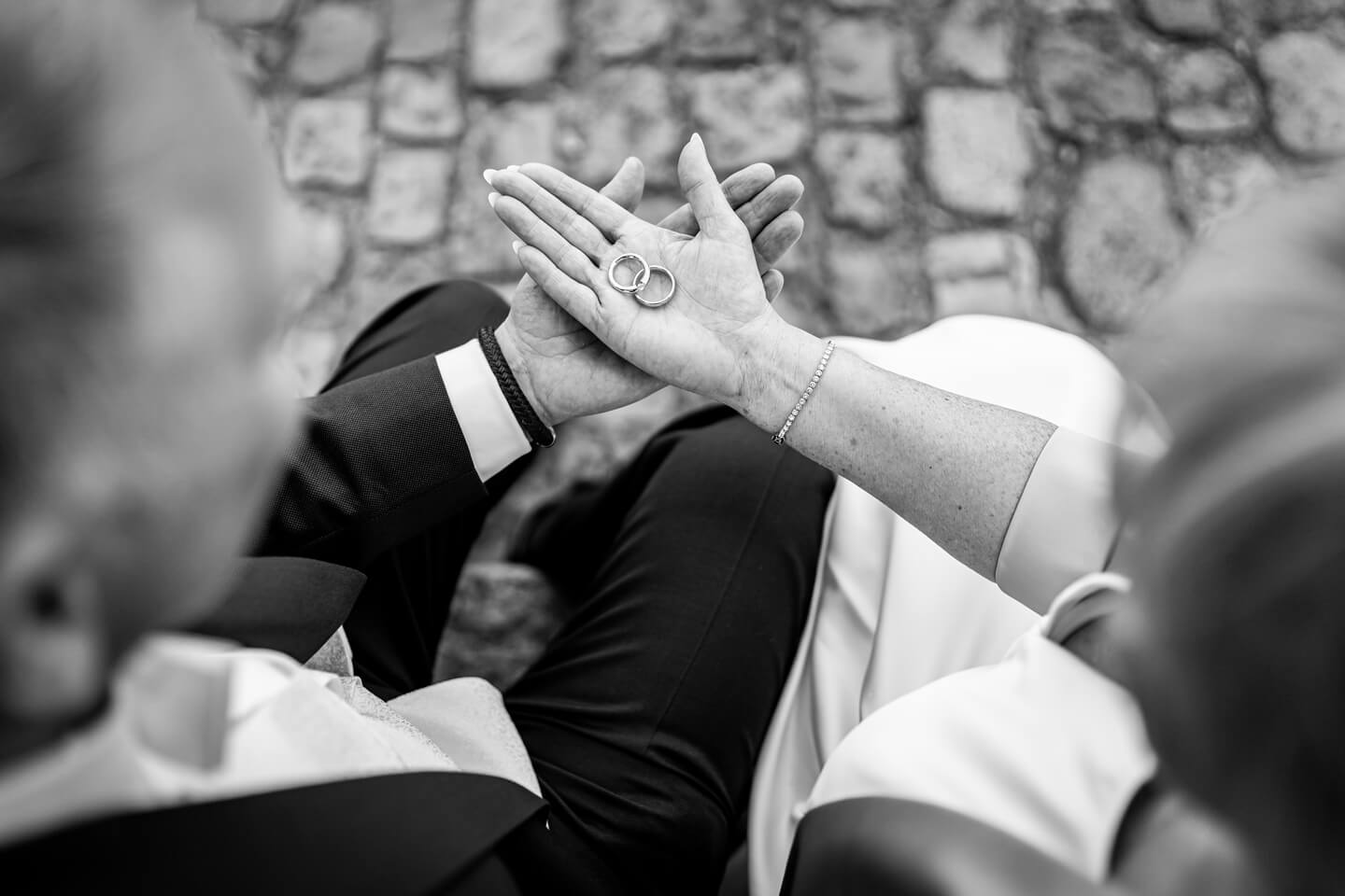 Schwarzweiß-Fotografie: Brautpaar hät die Trauringe in den Händen.