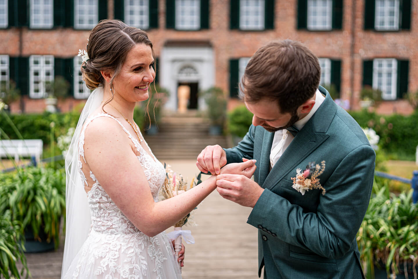 Bräutigam legt der Braut ein goldenes Armband beim First Look an.