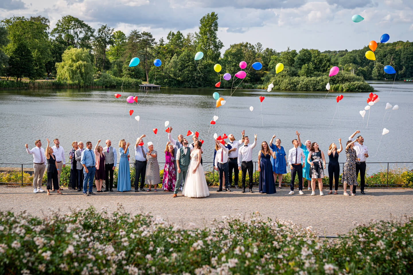 Hochzeitsgesellschaft mit bunten Ballons die in den Himmel steigen.