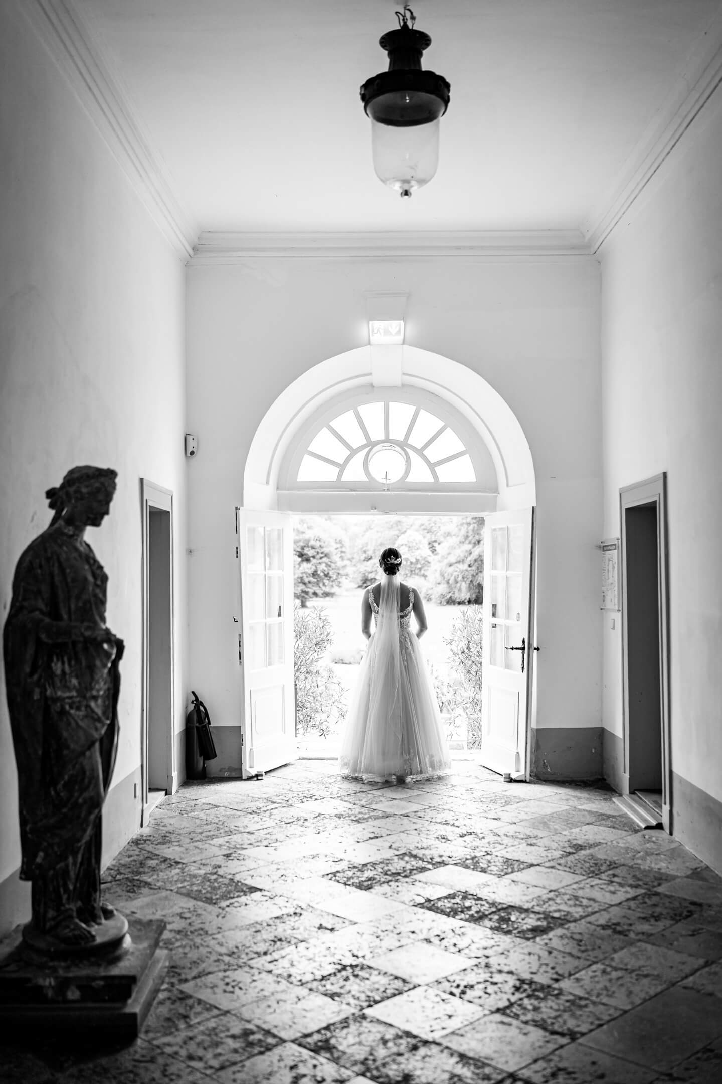 Braut steht an der Treppe vom Eutiner Schloss und blickt in den Schlossgarten.