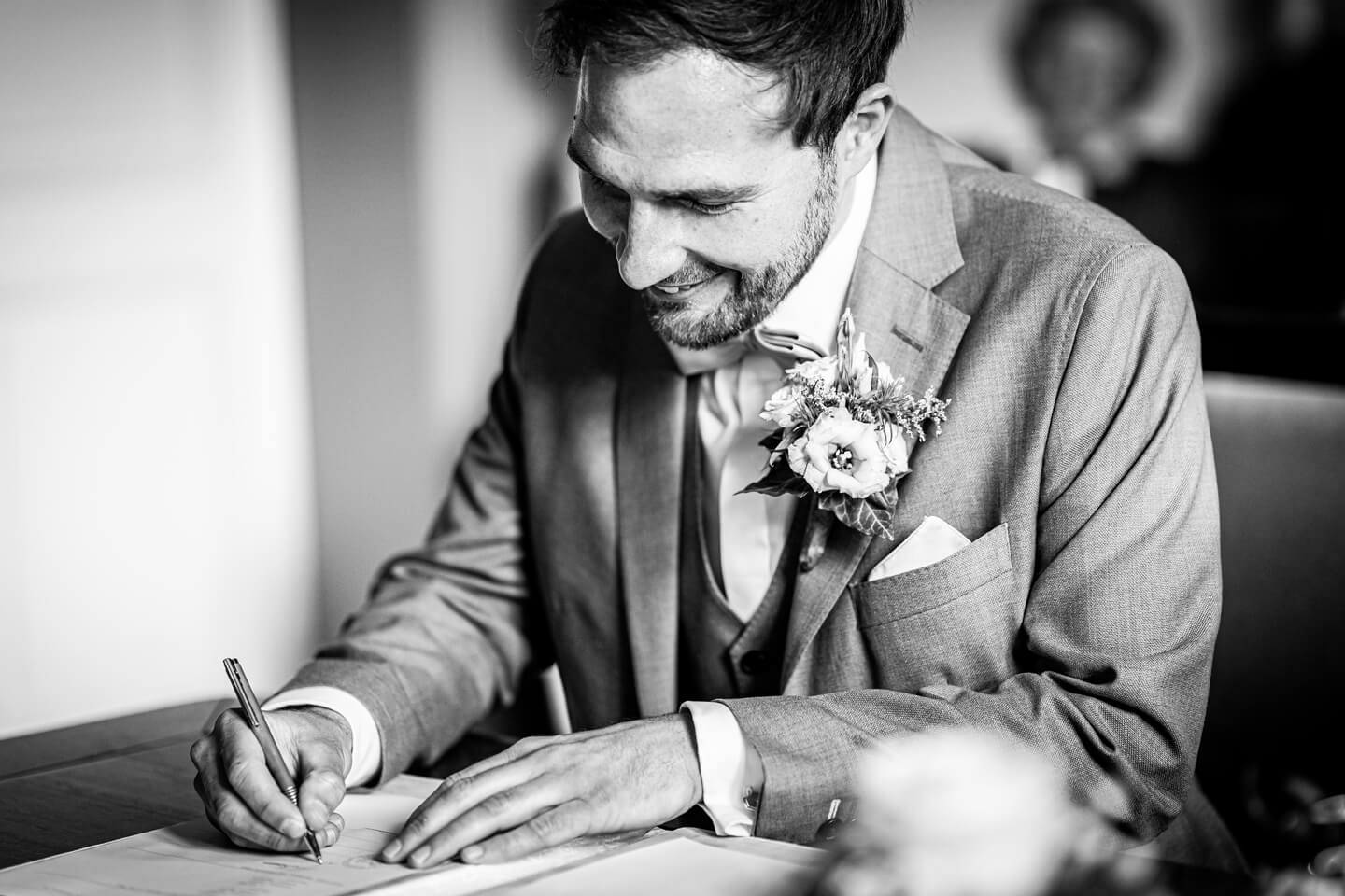 Bräutigam unterschreibt Heiratsurkunde.