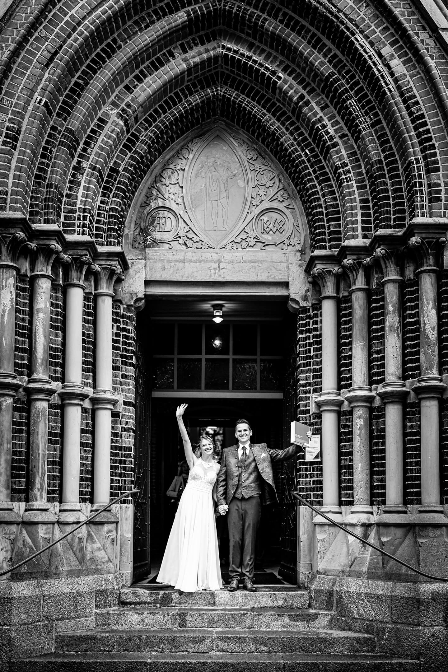 Frisch verheiratet! Brautpaar jubelt vor der Kirchentür.