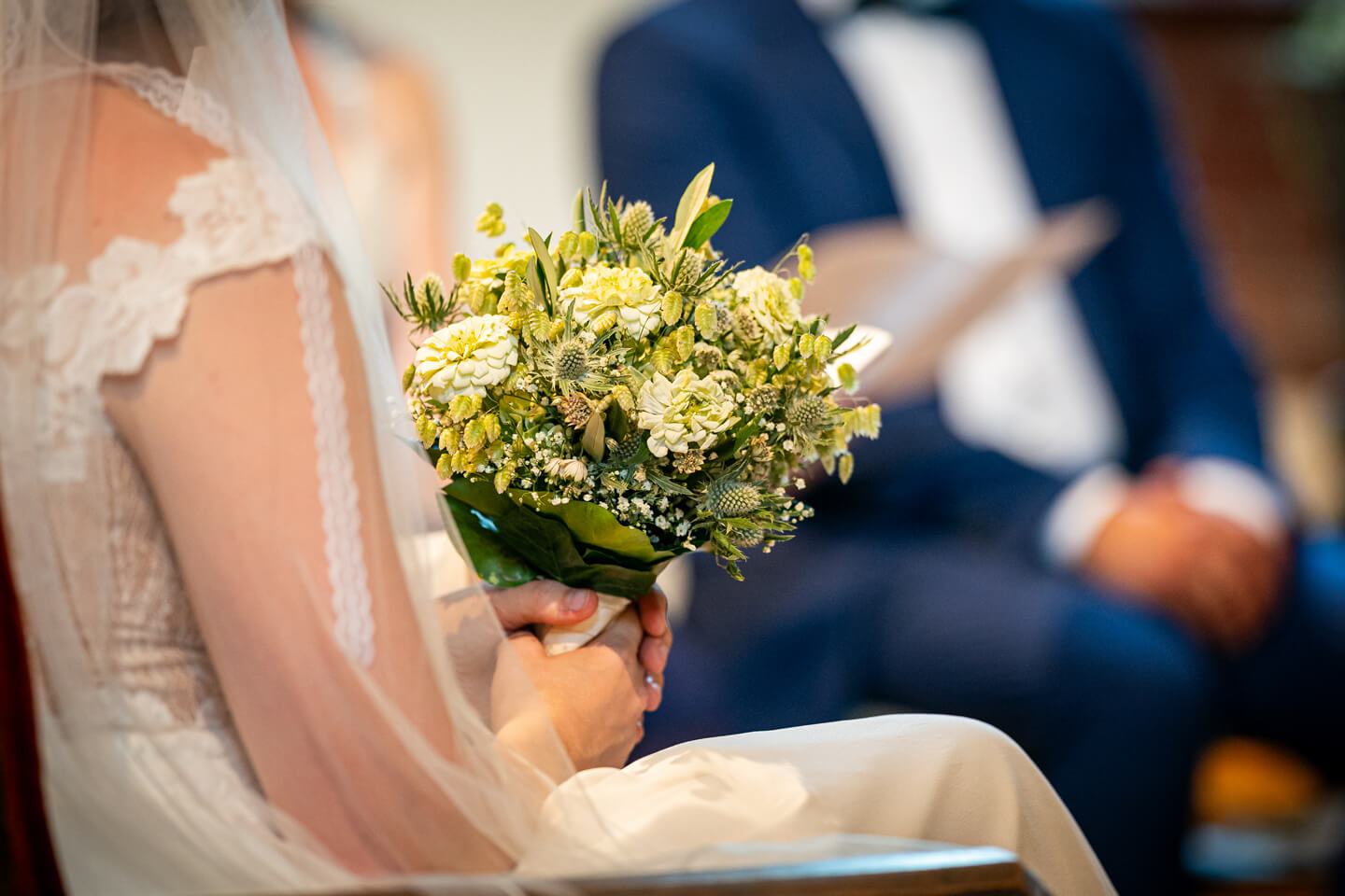 Braut hält ihren grün-weißen Brautstrauss in den Händen.
