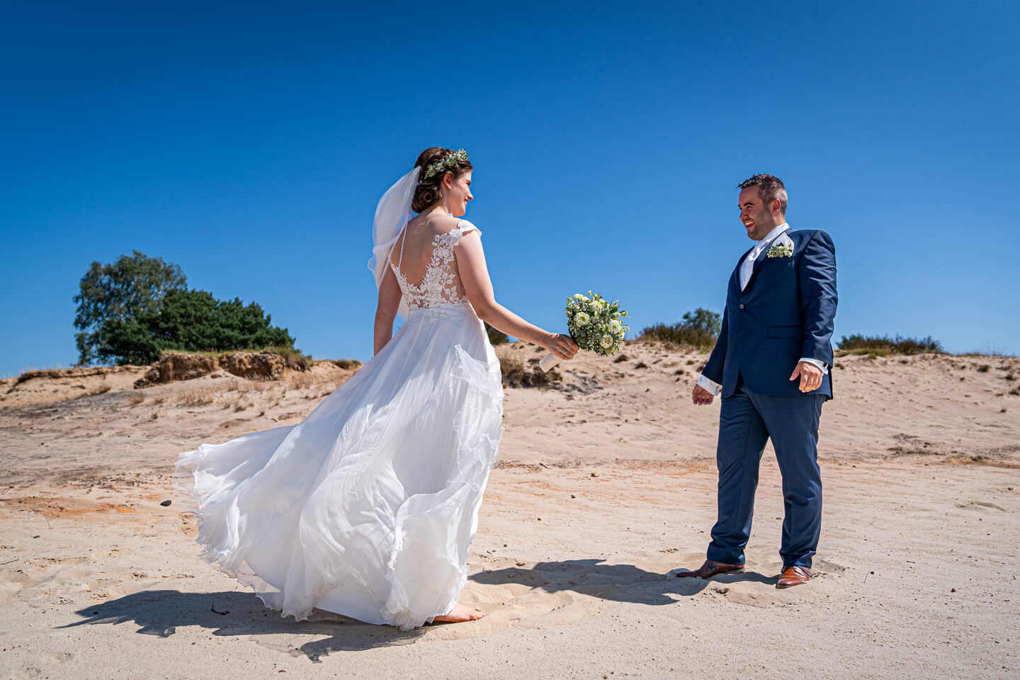 First Look vom Profi fotografieren lassen. Hier sieht sich das Hochzeitspaar erstmalig auf einer Sandfläche in der Heide.